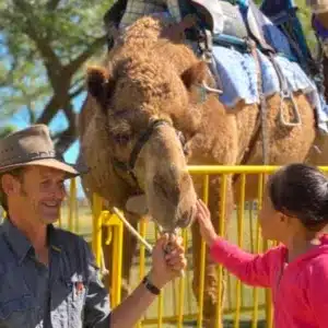 Child chatting with the farmer and camel