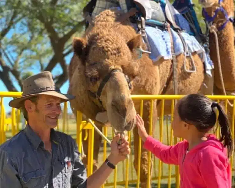 Child chatting with the farmer and camel