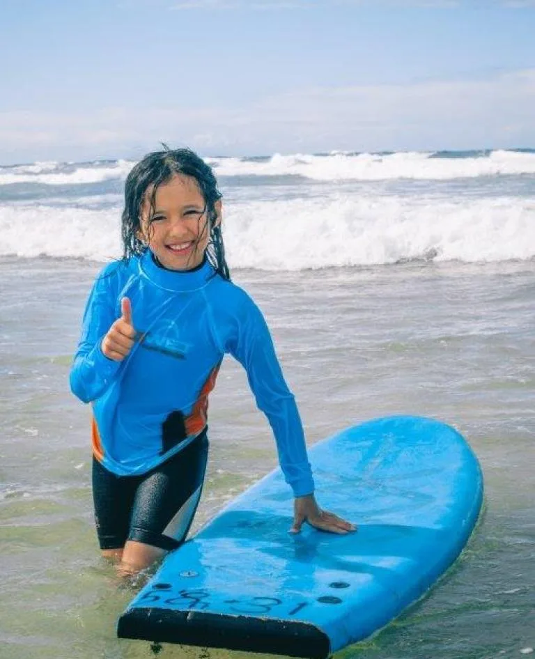 Girl gives thumbs up on surf session