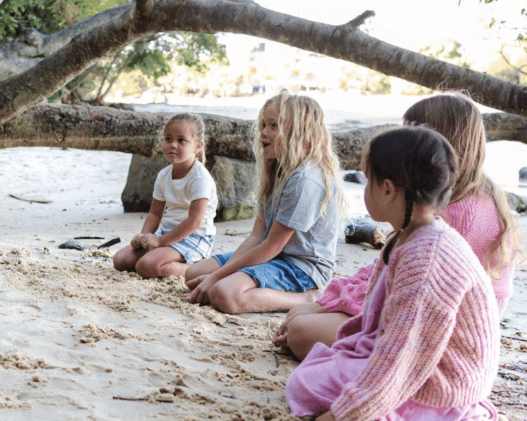 Young children sitting on Echo Beach at Burleigh Heads listening to stories of Jellurgal