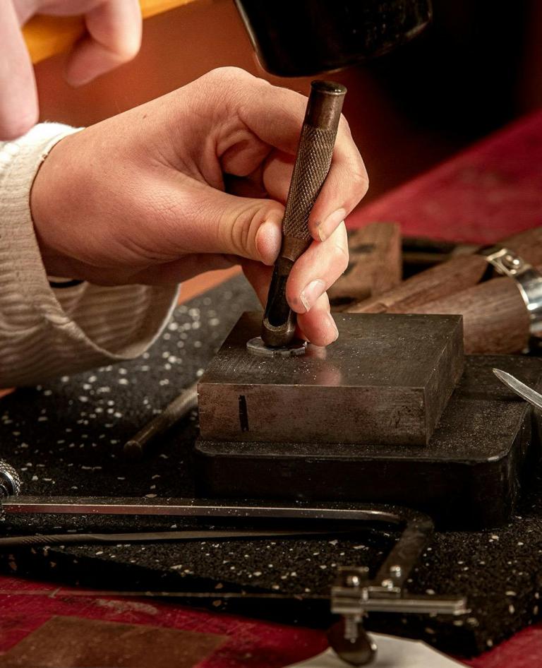 Teen participant using a metal stamping tool to engrave a design during Queensland Museum Cobb and Co hands-on jewellery making workshop